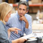 Two people discussing something on a clipboard