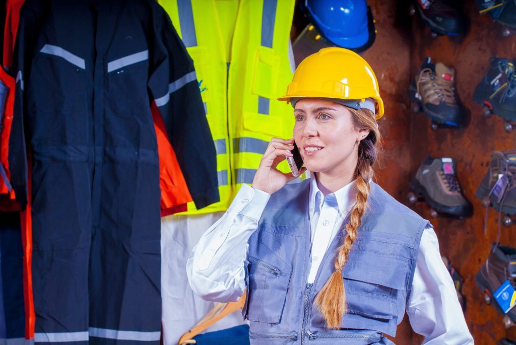 Woman working in telecom, wearing a hardhat and on the phone.